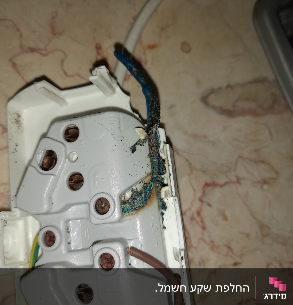 חוטי חשמל שרופים בתוך שקע חשמלי פתוח